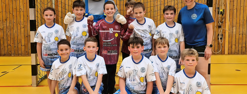 Die E-Jugend-Mannschaft des TB Pforzheim feiert ihren Turniersieg beim SWP-Cup 2025 in der Fritz-Erler-Halle – mit Pokal, Maskottchen und Trainerin.